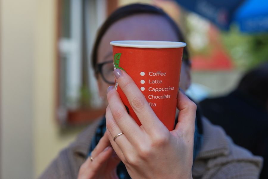 A picture of a woman holding a paper cup of coffee